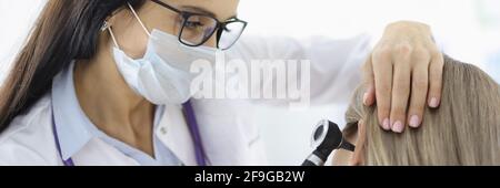 Otorhinolaryngologiste regardant les patients femelles oreille avec otoscope en clinique Banque D'Images