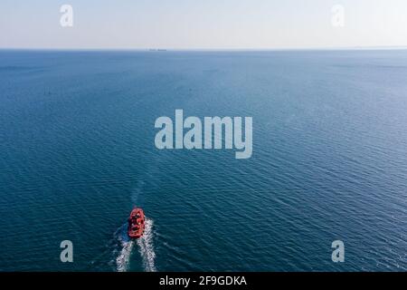 Le bateau-pilote orange va rejoindre le bateau sur les routes extérieures. Vue sur l'hélicoptère. Vue de dessus de la mer Banque D'Images