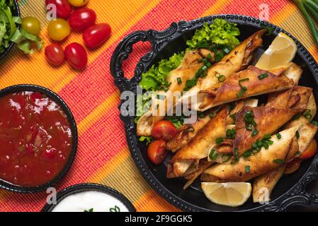 Petits tacos faits maison avec poulet, sauces en sauce et ingrédients alimentaires appelés taquitos Banque D'Images
