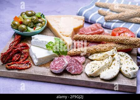 Viande et fromage cuits tapas espagnoles traditionnelles - jambon serrano, tranches de fromage de chèvre - servis sur un plateau de bois avec des olives et des bâtonnets de pain Banque D'Images