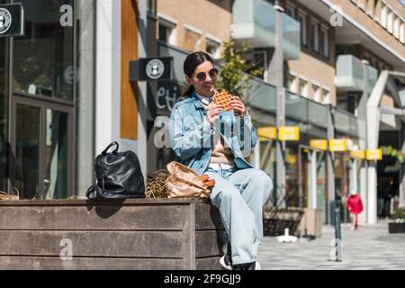 magnifique brunette 20-30s en savourant une délicieuse cuisine du restaurant à emporter la rue à l'heure du déjeuner Banque D'Images