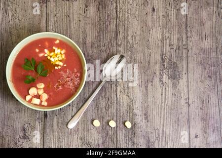 Zénith vue d'un bol de gazpacho avec des compléments et une cuillère à droite, et trois croûtons comme une ellipse (...). Concept de cuisine méditerranéenne, Hea Banque D'Images