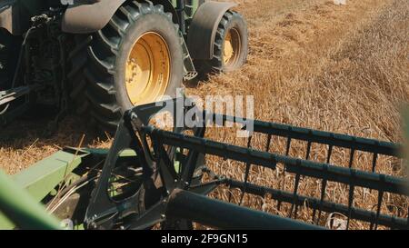 Gros plan de la barre de coupe d'une moissonneuse-batteuse dans le champ de blé pendant la journée. Une autre moissonneuse-batteuse peut être vue sur le côté gauche travaillant dans le champ, concept d'agriculture et récolte de récoltes. Banque D'Images