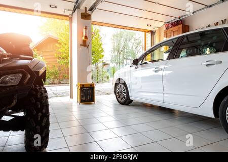 Home Suburban campagne moderne voiture et ATV double garage intérieur avec étagère en bois, outils et matériel entrepôt de stockage de substance à l'intérieur contre le soleil Banque D'Images