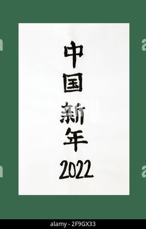 Nouvel an chinois 2022 calligraphie sur papier de riz et fond vert. La traduction se lit comme le nouvel an chinois 2022. Banque D'Images