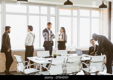 Silhouettes de personnes contre la fenêtre. Une équipe de jeunes hommes d'affaires travaillant et communiquant ensemble dans un bureau. Affaires professionnelles et Banque D'Images