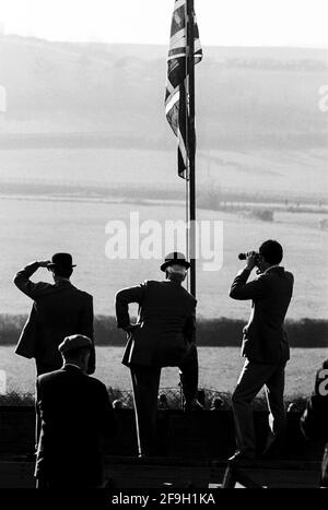 Royaume-Uni, Angleterre, Devonshire, Buckfastleigh, 1972. Des courses point à point ont eu lieu à Dean court sur les Dean Marshes, près de l'A38 entre Plymouth et Exeter. Deux stewards portant des chapeaux de bowler noirs et d'autres spectateurs regardant une course sous le drapeau de l'Union ou le drapeau de l'Union du Royaume-Uni. Banque D'Images