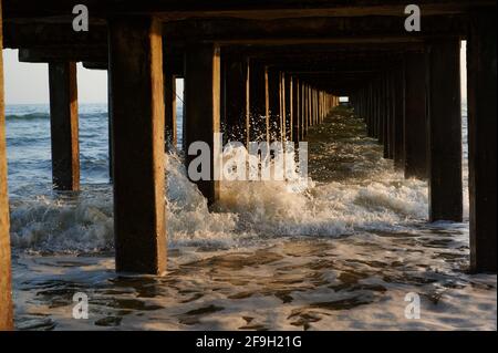 gros plan de la partie inférieure de la jetée sur le mer avec vagues le soir au coucher du soleil photo horizontale Banque D'Images