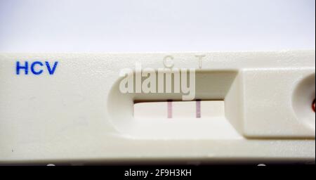 Un résultat positif pour la cassette du kit de test rapide de l'hépatite C qui vérifie les anticorps du virus de l'hépatite c détenus par une main du personnel médical Banque D'Images