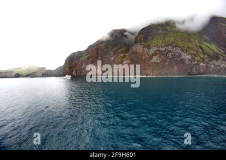 Bateau de croisière Galapagos amarré au loin, sous les montagnes au sommet du nuage au-dessus de la baie à Punta Vincente Roca, Isabela Island, Galapagos, Equateur Banque D'Images