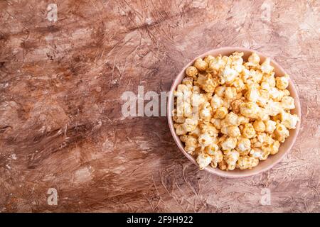 Pop-corn au caramel dans un bol en céramique sur fond de béton brun. Vue de dessus, plat, espace de copie. Banque D'Images