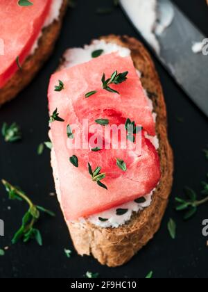 Toasts avec du fromage à pâte molle, de la pastèque et thym frais.salé sucré,fromage pastèque et épicé sur croquant de thym pain grillé tranches. Idée et recette pour un petit-déjeuner sain, inhabituelle en goûter d'été Banque D'Images