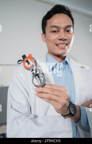 un médecin pose tenant un cadre de jauge à lunettes Banque D'Images