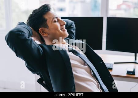 La femme d'affaires asiatique sourit avec assurance à côté de deux écrans d'ordinateur vierges Banque D'Images