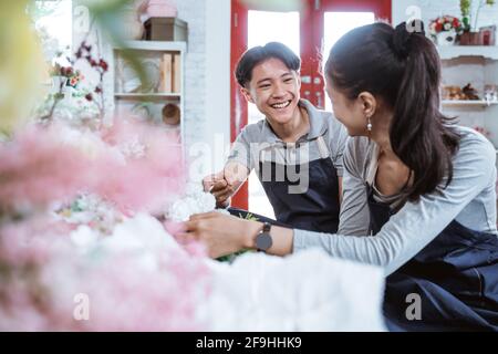 portrait jeune couple portant un tablier souriant parlant tout en travaillant ensemble Banque D'Images