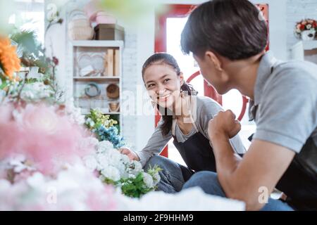 portrait jeune couple portant un tablier souriant parlant tout en travaillant ensemble Banque D'Images