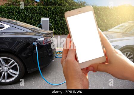 Mains avec un smartphone sur un fond de voiture de location à la station de charge pour les véhicules électriques. Partage de voiture. Banque D'Images