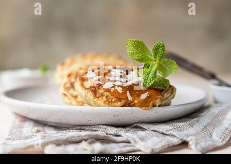 Crêpes d'avoine saines avec confiture, noix et menthe sur plaque en céramique. Repas de petit-déjeuner végétalien. Mise au point sélective. Banque D'Images