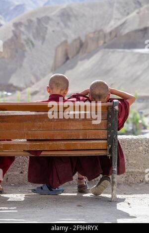 Deux jeunes moines bouddhistes reposant sur un banc par une journée ensoleillée dans la rue à côté du monastère de montagne Lamayuru à Ladakh, dans le nord de l'Inde Banque D'Images