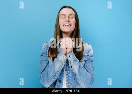 De jeunes femmes plein d'espoir se cramponnant à des poings en priant en demandant des rêves deviennent réalité, une femme vante en anticipation d'avoir le désir de croire en la bonne chance Banque D'Images