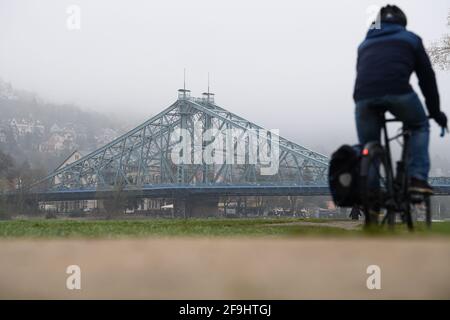 Dresde, Allemagne. 19 avril 2021. Un cycliste longe les prairies de l'Elbe dans le brouillard matinal devant le pont Blaues Wunder. Credit: Robert Michael/dpa-Zentralbild/ZB/dpa/Alay Live News Banque D'Images