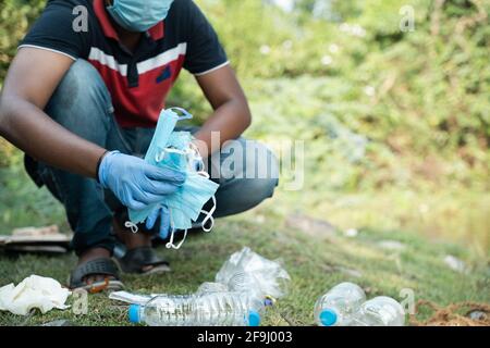 Travailleur de première ligne non reconnaissable ou collecteur de déchets occupé à séparer les déchets médicaux ou EPI de la litière en plastique pendant la pandémie de covid-19 du coronavirus. Banque D'Images