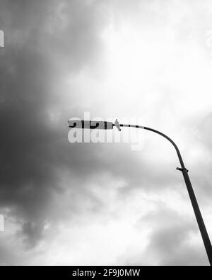 Prise de vue verticale en niveaux de gris d'un lampadaire sous le ciel nuageux Banque D'Images