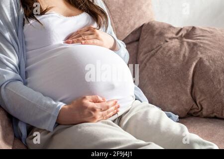 femme enceinte avec grand ventre avancé grossesse se reposant sur canapé à la maison.grossesse saine et bonne humeur Banque D'Images
