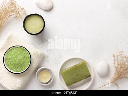 Sel de mer aromatique, gommage, savon à base de plantes et serviettes de bain sur fond blanc avec bougies et pierres. Concept de bien-être spa. Vue sur le dessus, espace pour les copies Banque D'Images