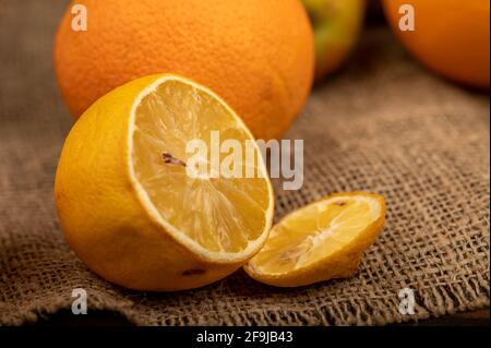 Émincé de citron et d'oranges juteuses fraîches sur un tissu à la maison avec une texture rugueuse. Mise au point sélective en gros plan. Banque D'Images
