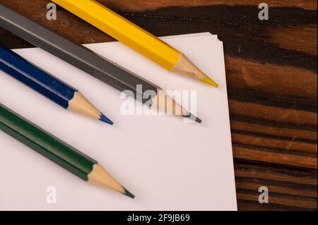 Crayons colorés et feuilles de papier blanches sur une table en bois. Mise au point sélective en gros plan. Banque D'Images