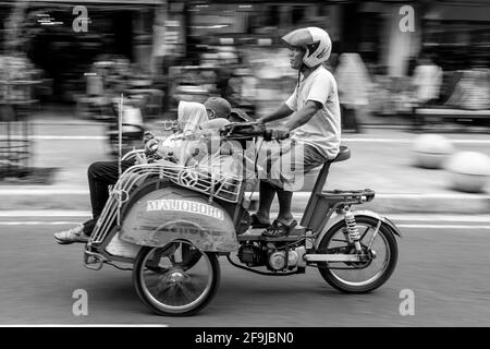 Taxi et passagers de moto, rue Malioboro, Yogyakarta, Indonésie. Banque D'Images