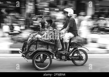 Taxi et passagers de moto, rue Malioboro, Yogyakarta, Indonésie. Banque D'Images