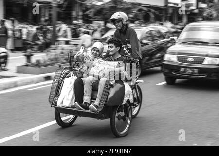 Taxi et passagers de moto, rue Malioboro, Yogyakarta, Indonésie. Banque D'Images