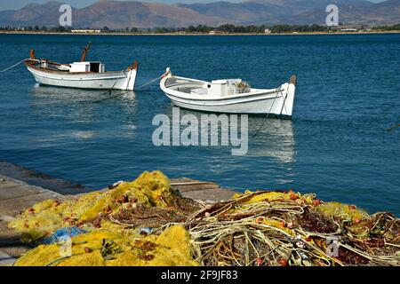 Paysage avec des bateaux de pêche traditionnels grecs et des filets de pêche au premier plan à Nafplion, Argolis Péloponnèse, Grèce. Banque D'Images