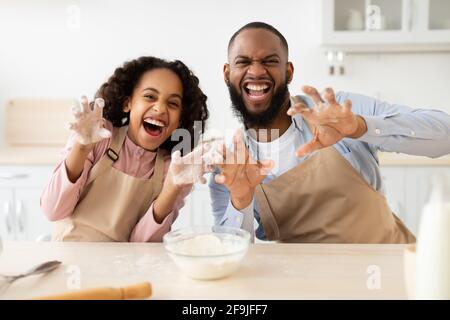 Homme noir et sa fille posant et jouant dans la cuisine Banque D'Images