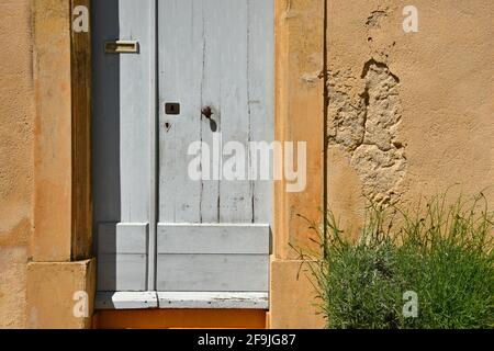 Façade de maison rurale typique de style provençal avec porte en bois sur un mur d'ocre dans le village pittoresque de Lourmarin dans le Vaucluse, Provence France. Banque D'Images