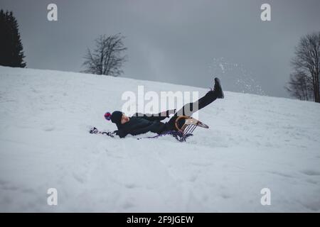 L'athlète tombe d'un traîneau en bois et tombe dur sur la neige et les entorses. Le traîneau du garçon s'est coincé et il l'a jeté et il a fait un somersault. Dur Banque D'Images