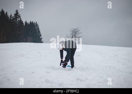 L'athlète tombe d'un snowboard en plastique et tombe dur sur la neige et les entorses. Le conseil du garçon s'est coincé et il l'a jeté et il a fait un somersault. Banque D'Images