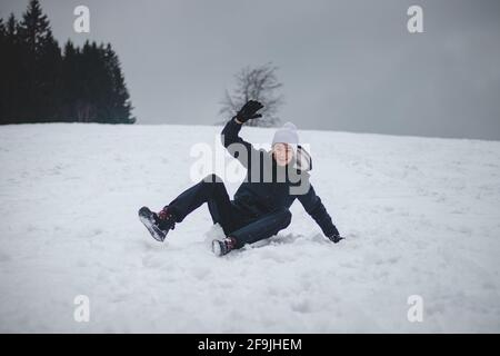 l'adolescent tombe d'un snowboard en plastique et tombe dur sur la neige et les entorses. Inventer des absurdités en quarantaine dans la neige. Conduite sur un unconventio Banque D'Images