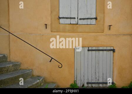 Façade de maison rurale de style provençal avec volets en bois gris sur un mur ocre dans le village pittoresque de Lourmarin dans le Vaucluse, Provence France. Banque D'Images