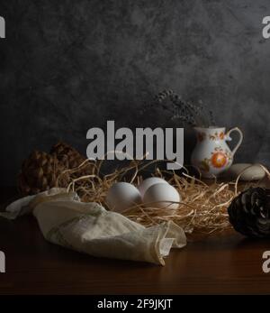 Œufs de poulet biologiques en nid avec champignons, oreilles de blé, maïs, cône de pin et lavande avec concept de photographie de nourriture sombre, concept de ferme Banque D'Images