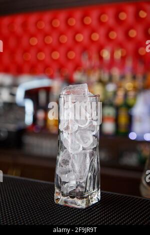 Un grand verre à boules rempli de glaçons se trouve sur le comptoir du bar. Banque D'Images