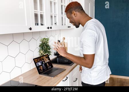 L'homme afro-américain utilise un ordinateur portable, il a une réunion vidéo avec des amis ou des collègues, leur saluant. Un homme joyeux, indépendant, est souriant Banque D'Images