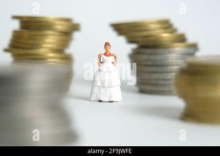 Robe de mariage budget pour mariée, miniature personnes illustration concept. Femme debout entre la pile de monnaie. Photo d'image Banque D'Images