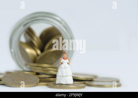 Robe de mariage budget pour mariée, miniature personnes illustration concept. Femme debout au-dessus du pot de monnaie. Photo d'image Banque D'Images