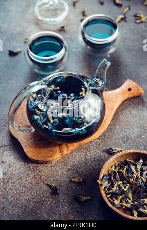 Thé de pois aux papillons thaïlandais dans une théière en verre et tasses sur une table. Banque D'Images