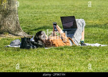 REGENT PARK LONDRES, ROYAUME-UNI. 19 avril 2021. Une femme couché sur l'herbe avec un ordinateur portable sous le soleil chaud sur Regents Park. Une mini-vague de chaleur a commencé à frapper Londres cette semaine car les températures plus élevées devraient atteindre 22celsius. Credit amer ghazzal/Alamy Live News Banque D'Images