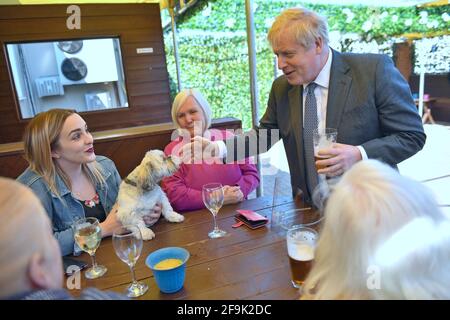 Le Premier ministre Boris Johnson accueille un chien de cuisine dans le café en plein air lors d'une visite au pub et restaurant Mount à Wolverhampton, dans les Midlands de l'Ouest, sur la piste de campagne électorale locale. Date de la photo: Lundi 19 avril 2021. Banque D'Images