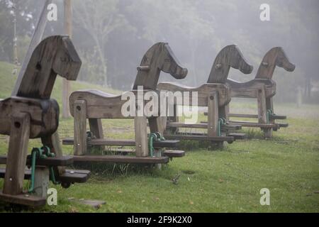 détails du paysage d'un parc avec jeux, chevaux en bois bordés de brume, objets Banque D'Images